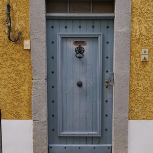 Porte en bois bleu cloutée entourée de pierres de taille sur un mur orange - France  - collection de photos clin d'oeil, catégorie portes